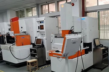 Two white and orange EDM machines on the left side of the tooling workshop