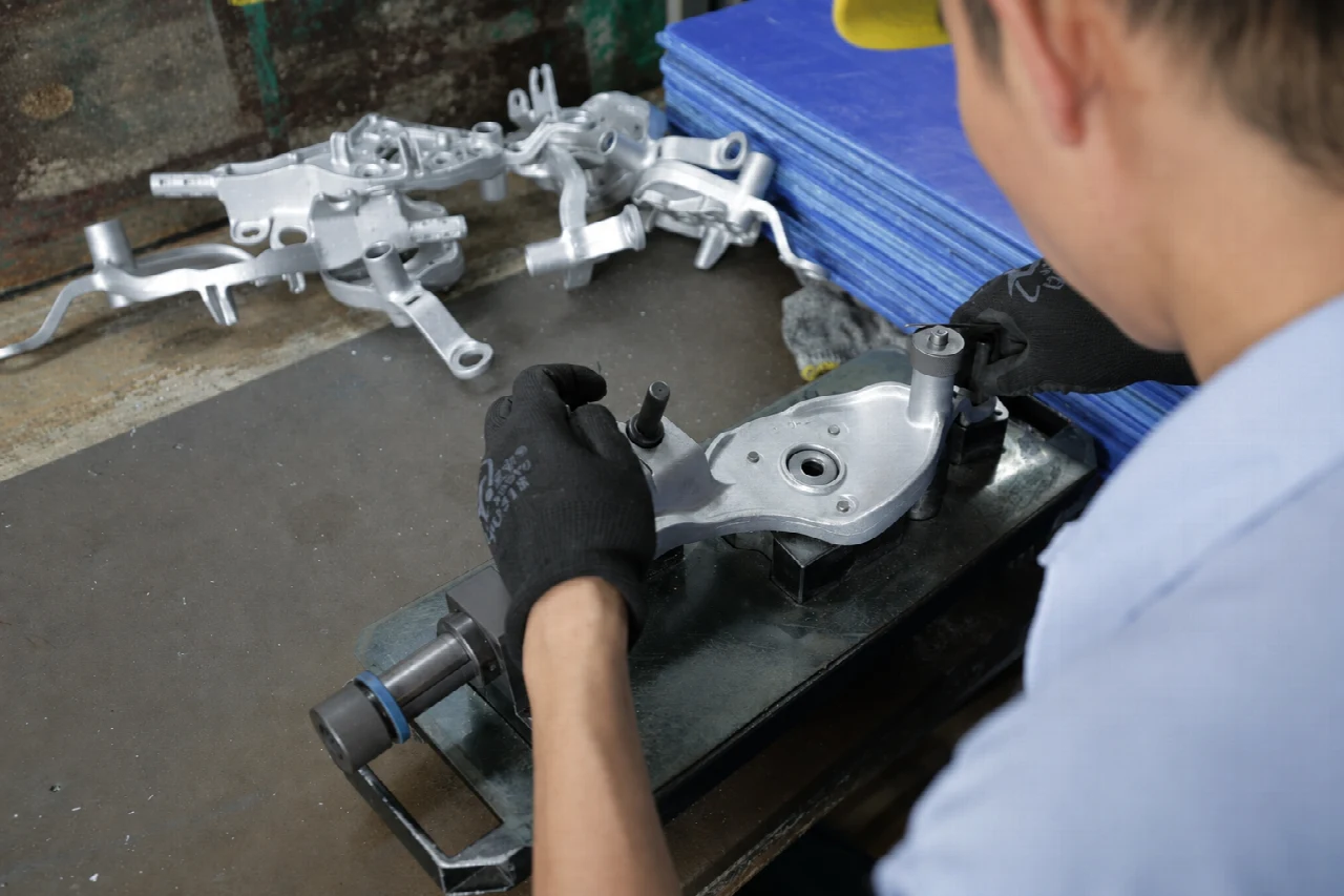 Operator positioning a metal component on a bench fixture